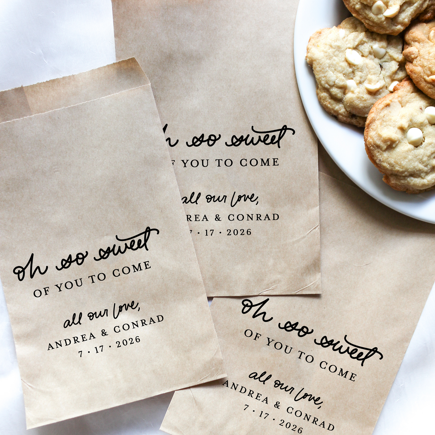 Personalized brown paper bags with black text next to a plate of cookies.