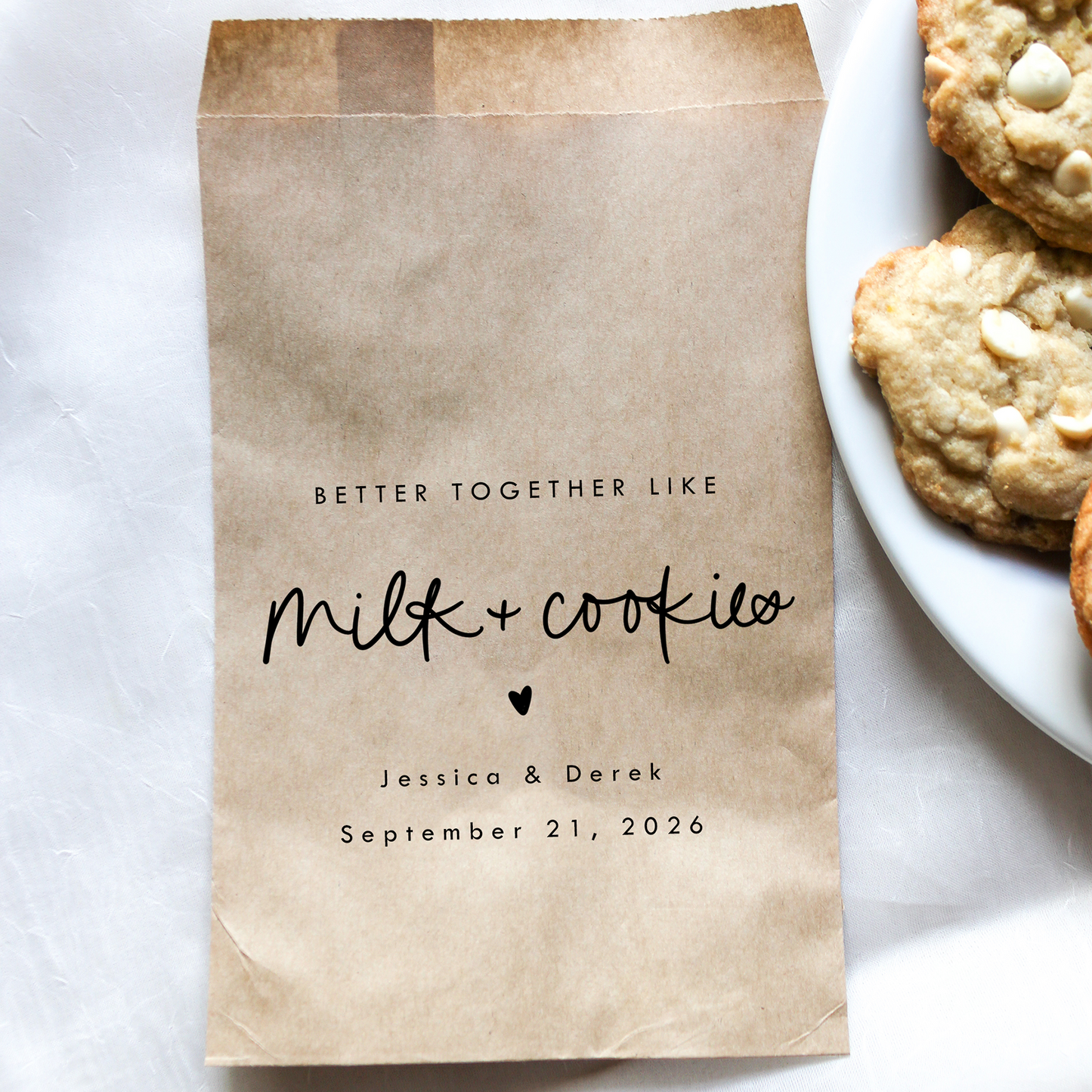 Personalized brown paper bag with 'Milk & Cookies' text next to a plate of cookies on a white surface