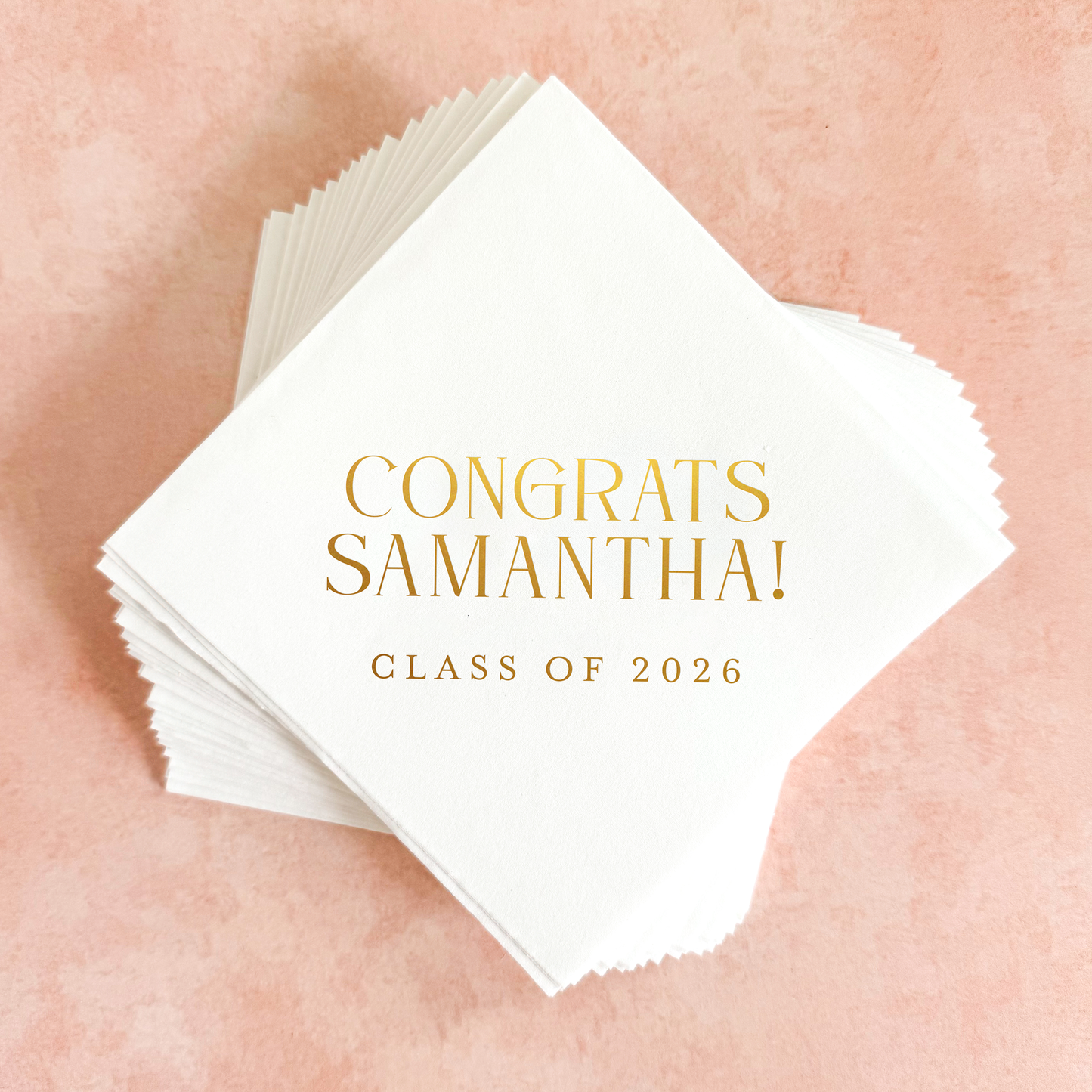 Stack of white napkins with 'Congrats Samantha! Class of 2026' text on a pink textured background