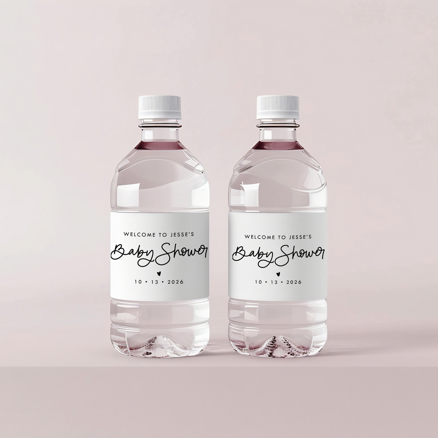 Two water bottles with baby shower labels on a light pink background