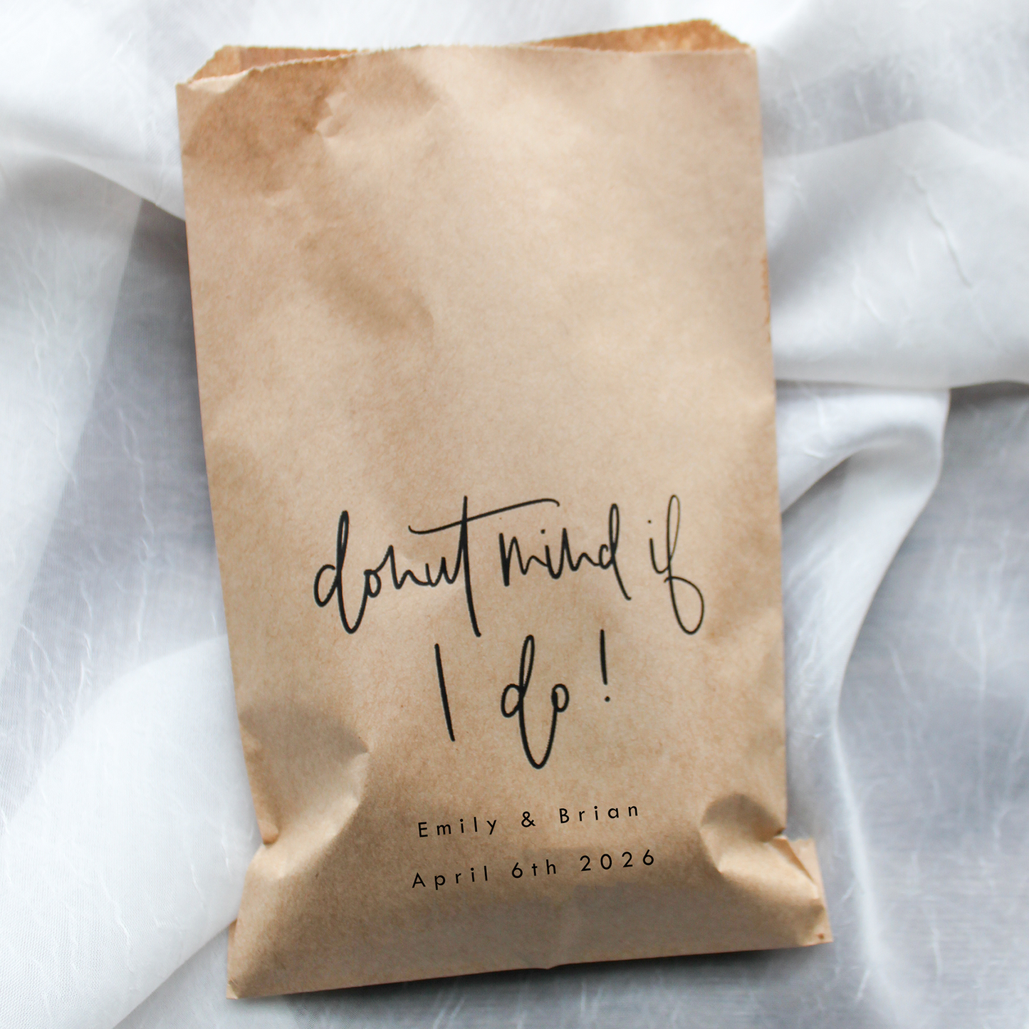 Brown paper bag with 'don't mind if I do!' text on a white fabric background