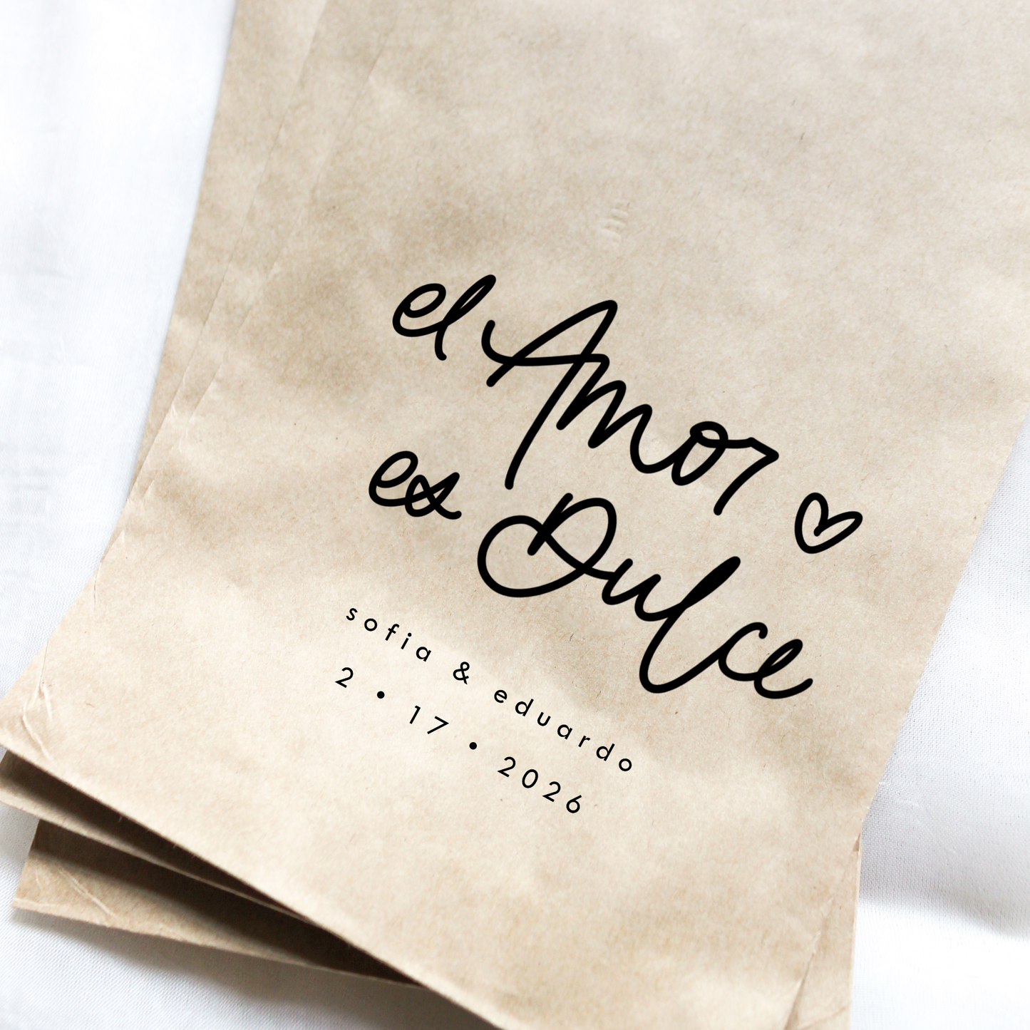 Kraft paper bags with 'el Amor es Dulce' text and personalized date on a white background