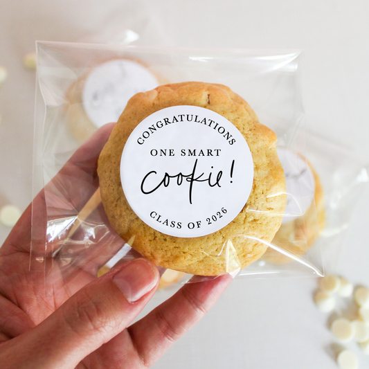 Hand holding a cookie with a 'Congratulations One Smart Cookie!' label against a light background