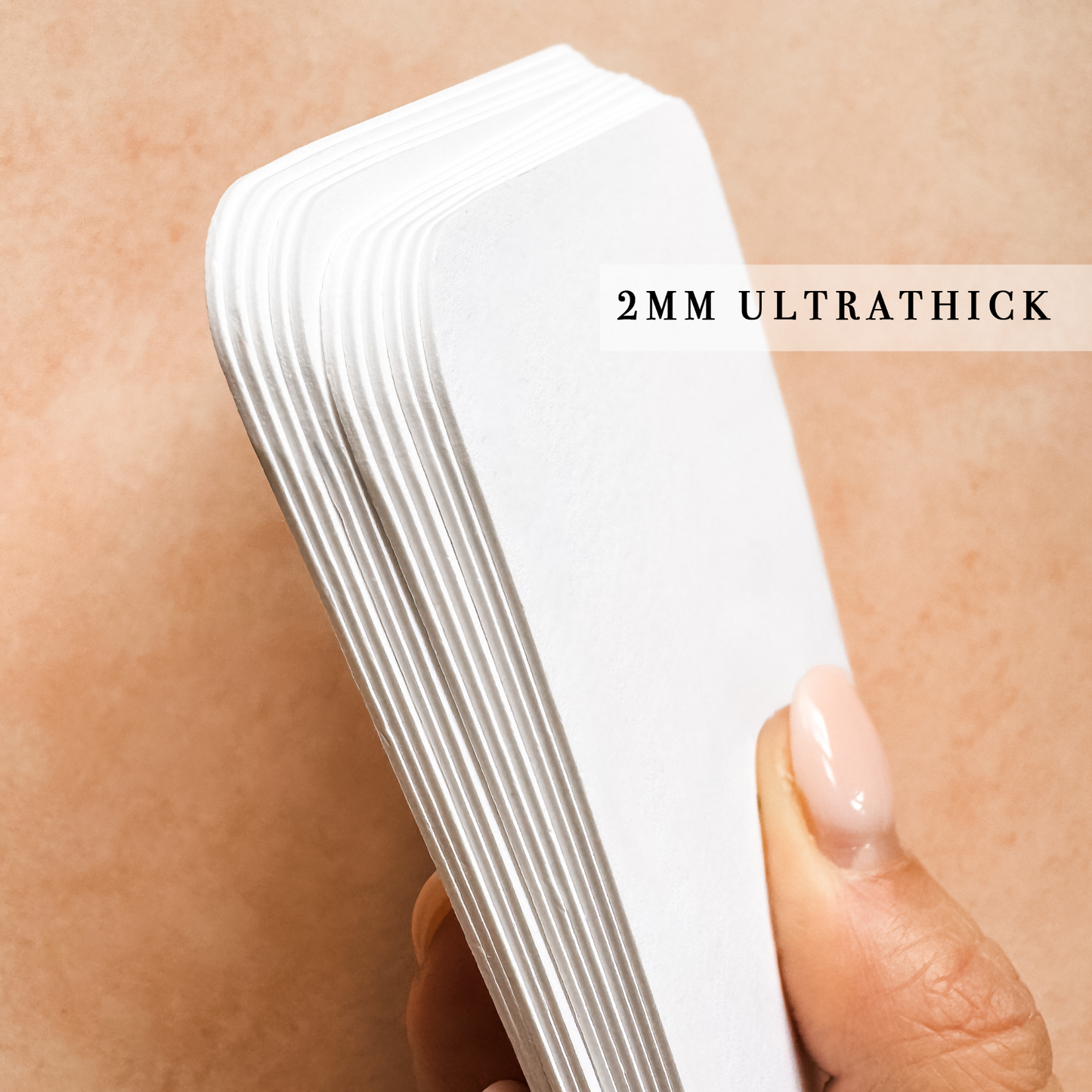 Hand holding a stack of 2mm ultrathick white paper against skin.