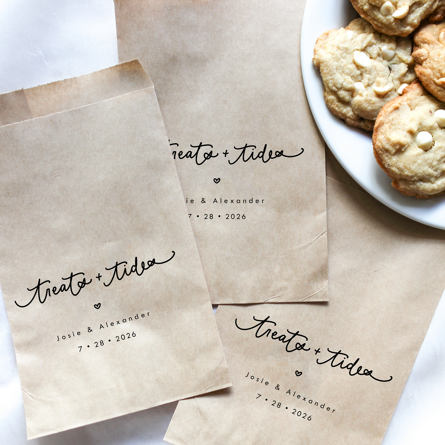 Brown paper bags with personalized text next to a plate of cookies